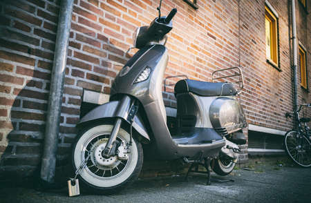 Scooter vintage italian moto. City transportation retro vehicle parked and locked with chain....