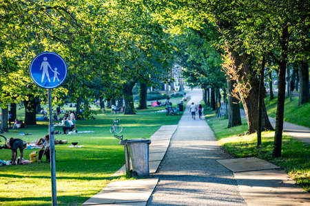 Rotterdam, Netherlands. June 29, 2019. People relaxing  on the grass, sun behind the trees foliage, summer afternoon in a city parkのeditorial素材