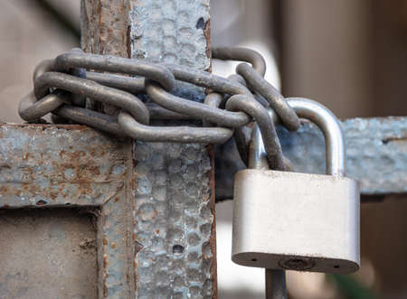 Padlock with chain closeup. Heavy metal lock on an entrance gate. Safety, security conceptの写真素材