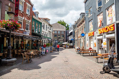 Utrecht, Netherlands - JULY 01, 2019: People walking and sitting in open air cafe on paved city street in center of aged city on summertimeのeditorial素材