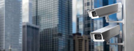 Surveillance CCTV Cameras. Security cam outdoors against blur buildings background, city center, banner, 3d illustrationの写真素材