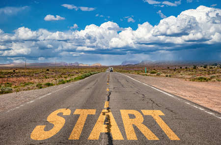 Start, new beginning concept. Text sign on a long straight highway in the american desert, blue cloudy sky backgroundの写真素材