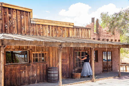 Calico ghost town California, USA. May 29, 2019. Woman in retro dress cleaning the glass window in a sunny spring dayのeditorial素材