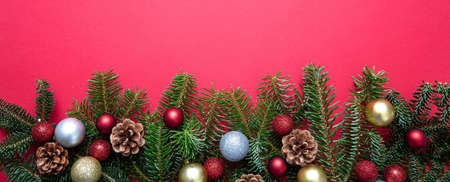 Christmas decoration. Fir tree twig fresh and ornaments garland against red color background,...