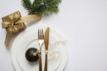 Xmas dinner table setting, Gold gift box and cutlery on white set of dishes, white background, top view, copy spaceの写真素材