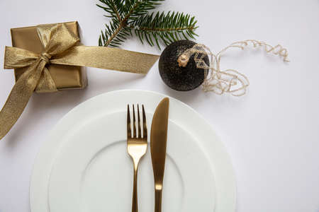 Xmas dinner table setting, Gold gift box and cutlery on white set of dishes, white background, top viewの写真素材