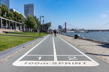 Rotterdam, Netherlands. June 28, 2019. Athletes riding bicycles in a sidewalk next to Nieuwe Maas with view of the Erasmus Bridgeのeditorial素材