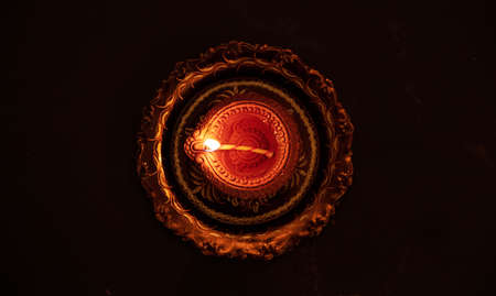 Diwali, Hindu festival of lights. Clay diya candle illuminated in Dipavali. Oil lamp on traditional...
