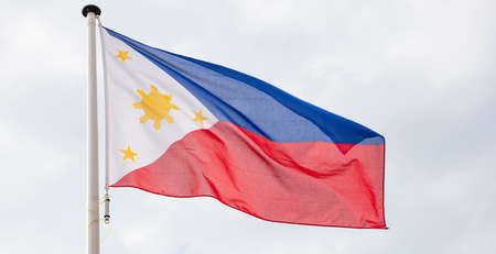 Philippines flag. Philippines national sign and symbol waving on a flagpole against cloudy sky backgroundの写真素材