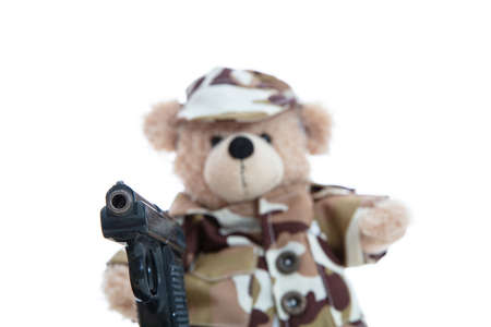 Army, military concept. Cute teddy bear in soldier uniform holding a gun standing isolated against...