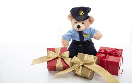 Police and christmas concept. Cute teddy bear in police officer uniform and xmas gift boxes isolated...