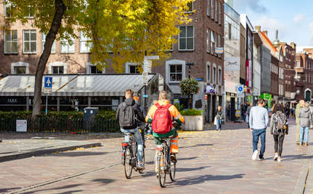 Eindhoven Netherlands, October 10, 2019. Rear view of people riding bikes, urban background, sunny autumn dayのeditorial素材