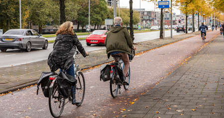 Rotterdam Netherlands, October 13, 2019. Rear view of people riding bikes, urban background, cloudy autumn dayのeditorial素材