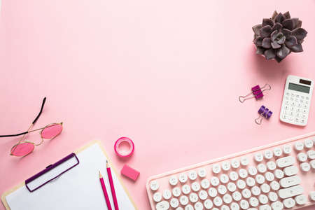 Female office desk. Computer keyboard and stationery against pink background, copy spaceの写真素材