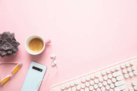 Woman office desk. Computer keyboard and smartphone against pink background, copy space