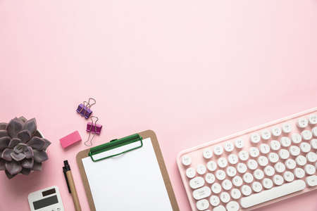 Woman office desk. Computer keyboard and notepad against pink background, copy spaceの写真素材