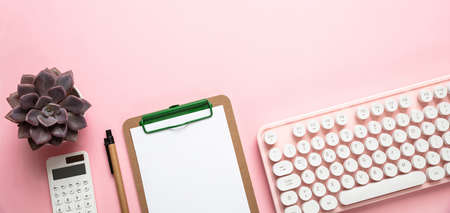 Woman office desk. Computer keyboard and notepad against pink background, copy spaceの写真素材
