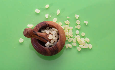 Mastic resin tears. Chios mastic in a wooden mortar isolated on green color backgroundの写真素材