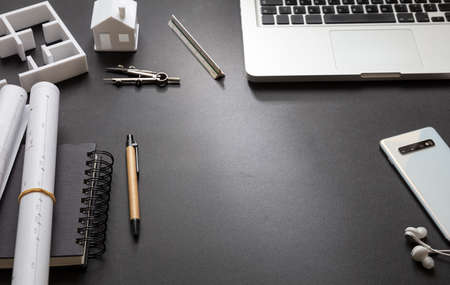 Architect engineer office desk. Blueprint plans and house model on black background, Residential building project, copy spaceの写真素材