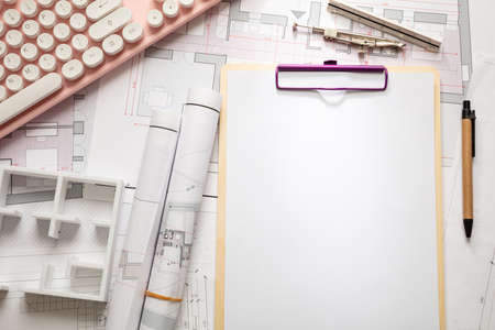 Female architect engineer office desk. Blueprint plans,  blank notepad and a pink computer keyboard, copy space, top viewの写真素材