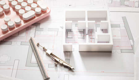 Female architect engineer office desk. Blueprint plans,  building project architectural design and a pink computer keyboardの写真素材