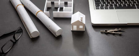 Architect engineer office desk. Blueprint plans and house model, Residential building project in...