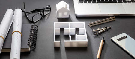 Architect engineer office desk. Blueprint plans and house model, Residential building project in...