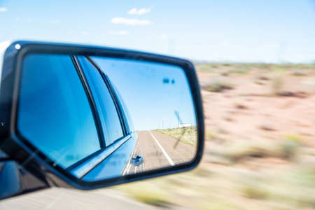 Driving on a highway in the US desert. Freeway reflected in a car wing mirror in a spring day, blur desert backgroundの写真素材