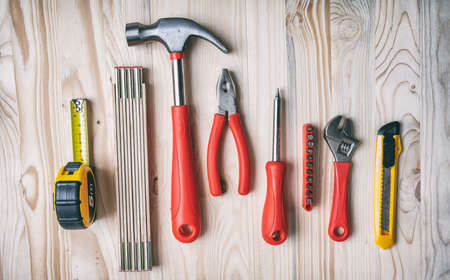 Hand tools set red and yellow color on wood, top view. DIY, repair, service concept.