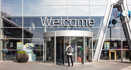 Eindhoven Netherlands. October 14, 2019. Welcome text sign at the Eindhoven airport terminal facade. Young man with backpack at the entrance, sunny autumn day.のeditorial素材