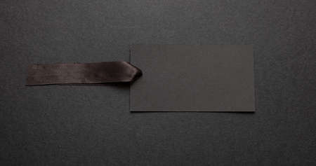 Black Friday sale concept. Black price tag blank mockup with satin ribbon isolated against black...