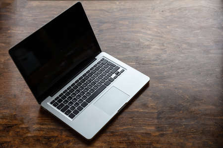 Computer screen mockup. Laptop with black blank screen on a wood desk background, copy space, high angle viewの写真素材