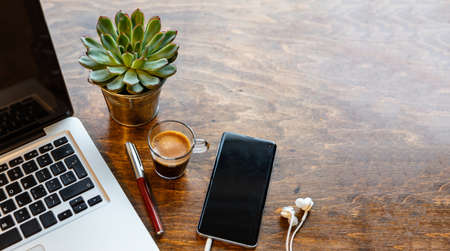 Office desk, cozy warm workspace. Computer laptop and mobile phone on a chestnut wood table, copy spaceの写真素材