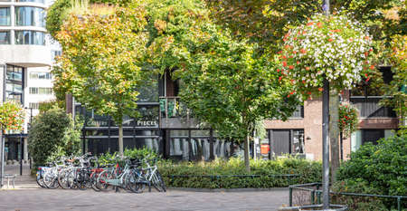 Eindhoven, Netherlands. October 10, 2019. An empty paved plaza of the city hosts parked bikes. Ecological and healthy lifestyle for the citizens. Buildings background.のeditorial素材