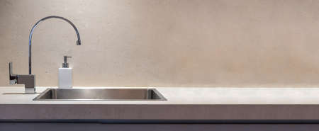 Kitchen modern interior detail. Kitchen sink and water tap front view, Stone beige color countertop banner, copy spaceの写真素材