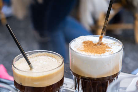 Freddo espresso and capuccino. A couple of tall glasses with cold instant coffee and black straws for a couple. Time to relax. Close up view, blur background.の写真素材