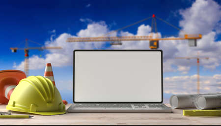 Blank laptop screen and engineering tools on an architect engineer desk, mockup template, blue sky background. Construction site office. 3d illustrationの写真素材