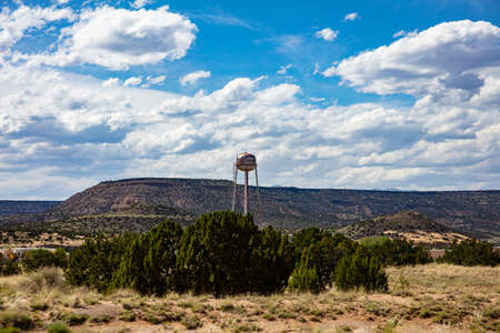 Chinle, Arizona, USA. May 17, 2019. Big, rusty water tank on a tower near the city, reminds us of the old western usa. Hill and cloudy sky background.のeditorial素材