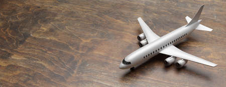 Plane model on wood floor background. Flight for business trip travel, tourism. Copy space, banner. 3d illustrationの写真素材