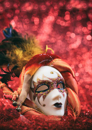 Carnival mask female theatrical face against red bokeh background. Mardi gras party celebration, theatrical costume conceptの写真素材