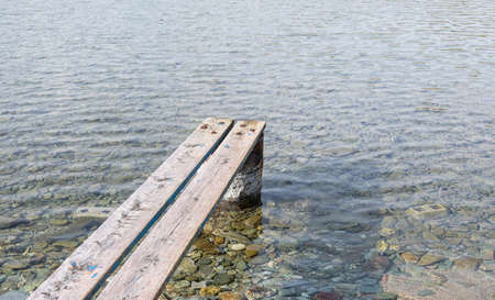 Weathered wooden small pier. Wood planks set properly on rusty barrel to make a mini platform over a...