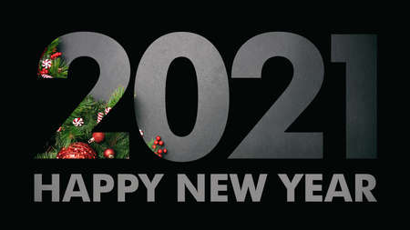 2021 New year eve. Black paper cut out number 2021 layer against Christmas ornaments on grey...