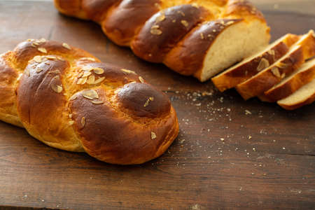 Sweet bread, easter tsoureki cozonac sliced on wood table background, closeup view. Braided brioche,...