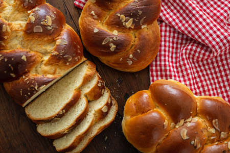 Sweet breads, easter tsoureki cozonac sliced on wood table background, top view. Braided brioche,...