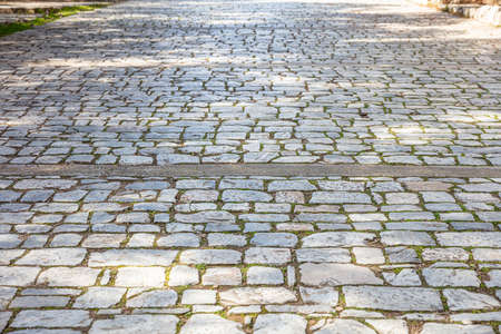 Old stone marble paved footpath, cobblestone pathway background, texture. Perspective high angle viewの写真素材