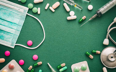 Medical supplies flat lay. Drugs medicine and syringes, stethoscope and thermometer, green background, top viewの写真素材