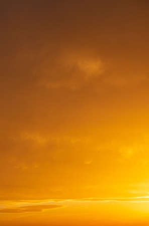 Sunset sky. Sunrise paints with orange shades the cloudy sky background.の写真素材