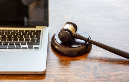 Auction law gavel and a computer laptop, wooden office desk background, closeup view, Online...