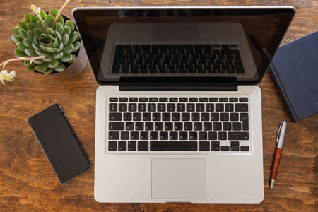Workplace. Computer laptop and mobile phone on a wood office desk, work from home concept, top viewの写真素材