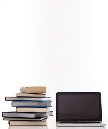 E learning concept. Books stack and an open computer laptop with black blank screen isolated on...